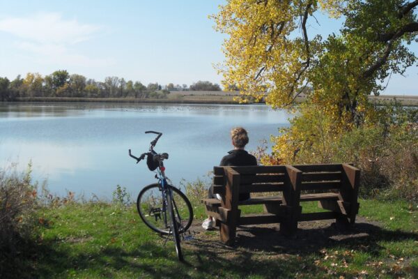 bike rider sitting on a bench near a lake