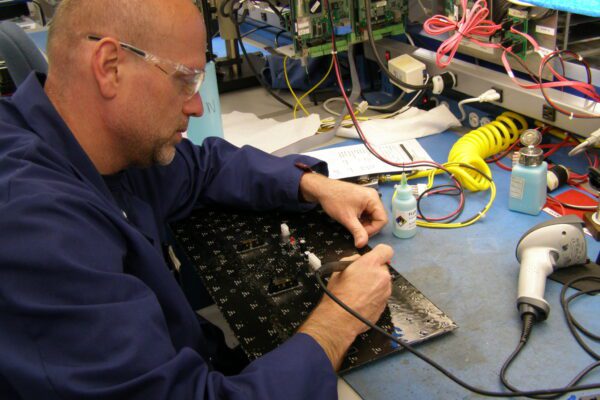 A man in safety glasses works on an electrical element at the Daktronics manufacturing plant in Redwood Falls.