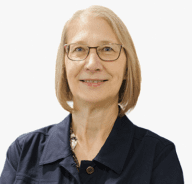 A smiling woman with short blonde hair and glasses, wearing a dark collared shirt, poses in front of a plain, light background.