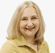 A smiling woman with straight, shoulder-length blonde hair wearing a light yellow collared top, posing against a plain white background.