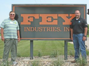 Mike Fey ss pictured with his father, Norm Fey, standing next to the Fey Industries sign.