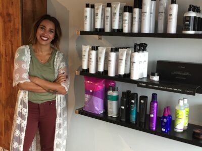 Salon owner Emma stands near a display of hair products in her shop