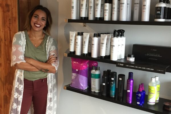 Salon owner Emma stands near a display of hair products in her shop