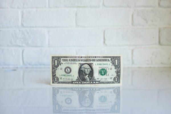 Dollar bill balanced in front of a white brick wall