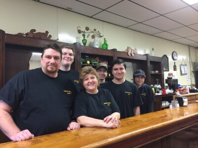 Restaurant owners Mark and Nancy stand behind the bar with their four children