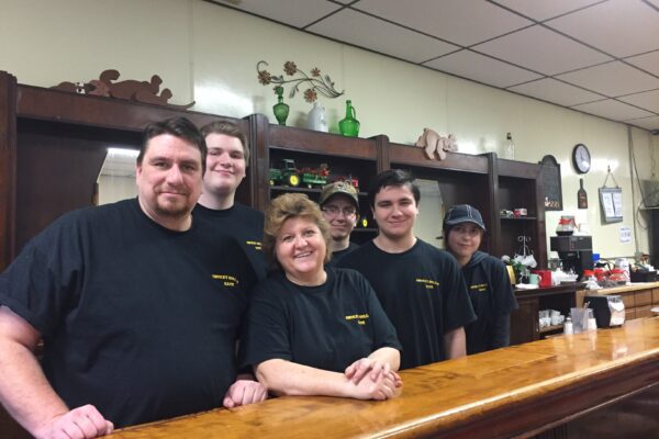 Restaurant owners Mark and Nancy stand behind the polished wood bar with their four children