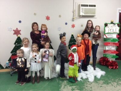 a group of kids and adults standing in a row wearing Christmas costumes