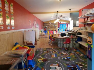 the interior of a child care filled with toys, art, small furniture and games
