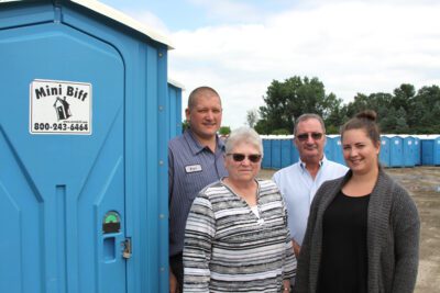 Standing outdoors next to a blue Mini Biff are employees Bryce Rusch, LuAnn Rusch and Mahri Schmit with owner John McGreavey.