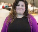 Adry is pictured wearing a black shirt and purple cardigan.
