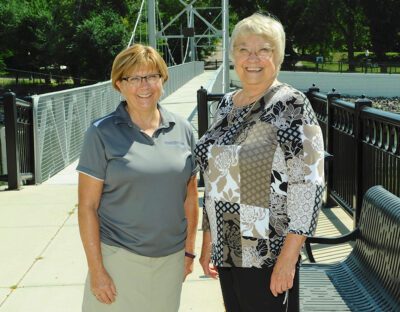 Peg and Avis are pictured standing next to one another in front of Granite Falls' iconic foot bridge.