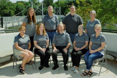 Nine of the current board members for the Granite Falls Area Community Foundation pose in two rows in front of the city's iconic foot bridge.