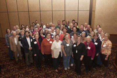 A large group of volunteers and foundation staff gather for a photo in a conference room at a fund partner training event