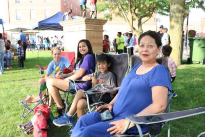 Kids and a grown-up sit in lawn chairs at the Worthington International Festival.