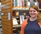 Emily stands in front of bookshelves at the library