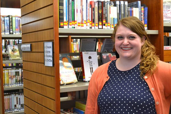 Emily stands in front of bookshelves at the library