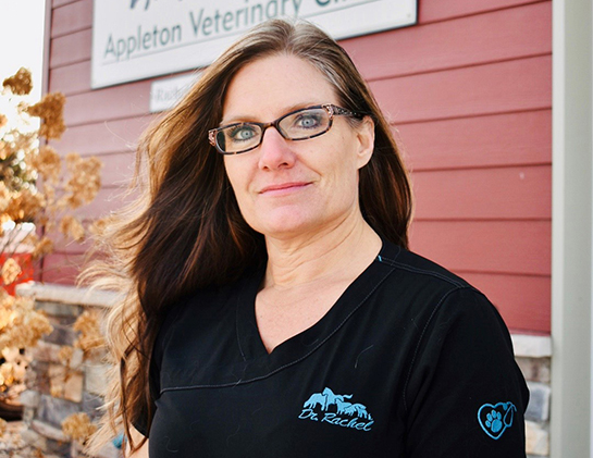 Rachel stands outside in front of the sign on the face of her veterinary clinic