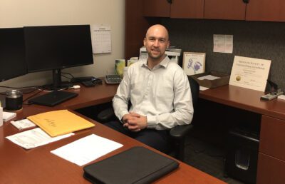 Matt Dostal, CPA, sits near a computer, behind a brown desk in his office