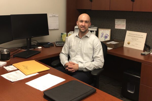 Matt Dostal, CPA, sits near a computer, behind a brown desk in his office