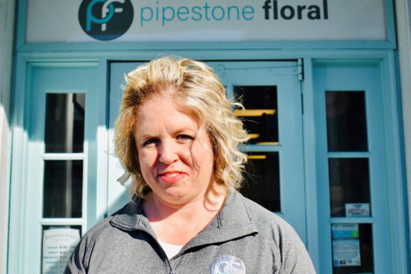 Gina stands in front of the Pipestone Floral shop front on a sunny day