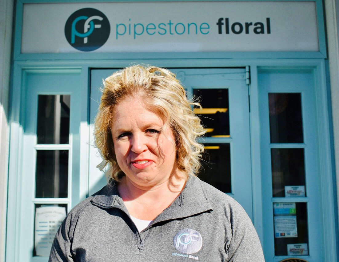 Gina stands in front of the Pipestone Floral shop front on a sunny day
