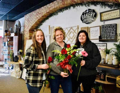 Gina and her team hold flowers inside the shop