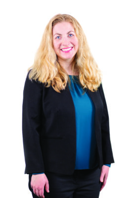 Initiators Fellow Erin Schutte Wadzinski poses for a formal head shot in front of a white background wearing a blue blouse under a black blazer