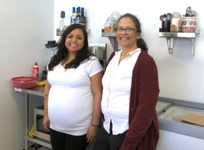 Karina and Debbie stand in front of a food prep area in the Taste in Time soda fountain.