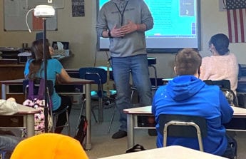 Mr. Lindstrom stands in front of his classroom teaching with a Swivl robot in the foreground.