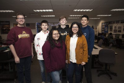 A group of students stand together in their high school computer lab.