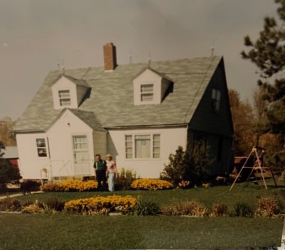 An old photograph shows a farmhouse with two people out front