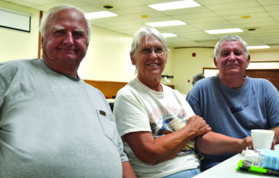 Virgil, Barb and John sit at a table in the community center