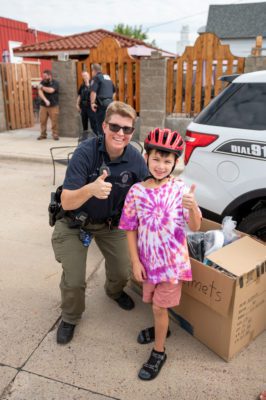 A child and a police officer give a thumbs up after the child gets fitted for a bike helmet