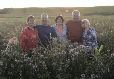 A group of family members stand with their arms around one anotherin a field of tall plants.