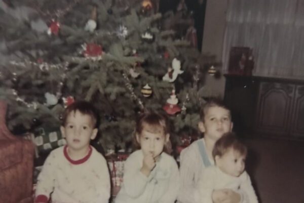 Four children sit in front of a Christmas tree in a vintage photo