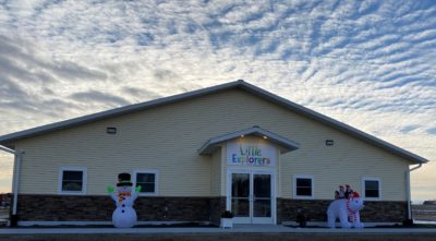 The Little Explorers Child Care Center building with clouds and sunrise in the background