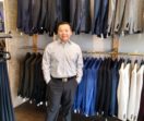 Sean stands in front of two racks of suit jackets in a variety of colors.