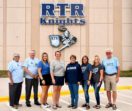 RTR Educational Foundation Advisory Board members stand in front of the school in spirit wear