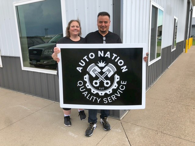 Wendi and Ruben Valdez holding new Auto Nation shop sign