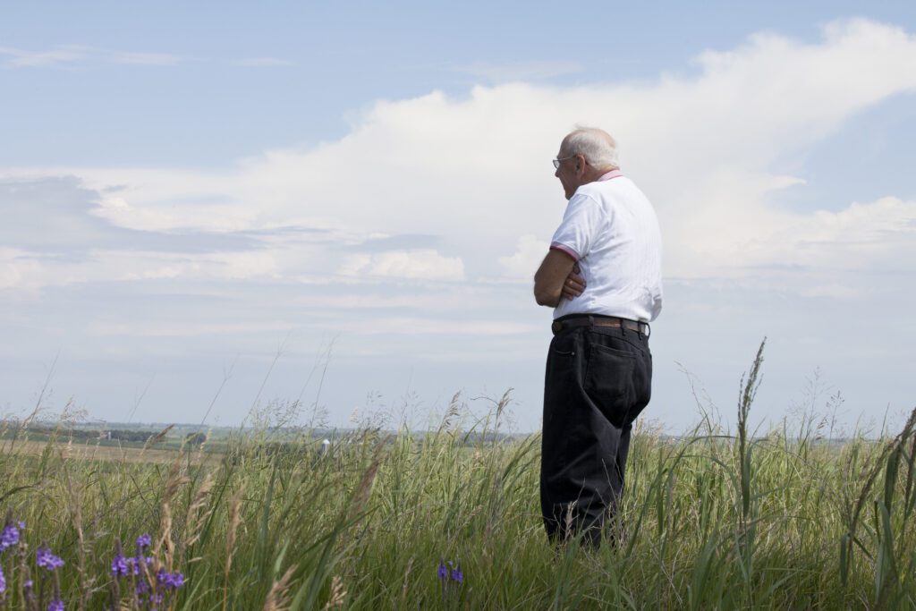 senior male standing in a grassy field