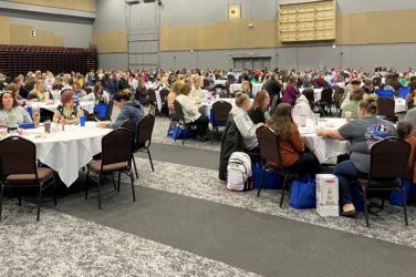 A view of the attendees seated around tables at the Kids First Conference.