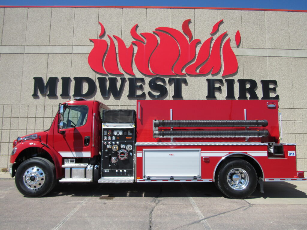 A fire truck parked in front a building with the Midwest Fire logo visible above it.