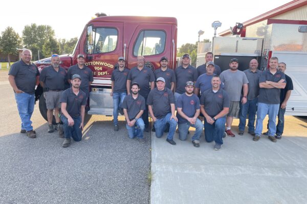 Members of the Cottonwood Fire Department pose for a group photo with a fire truck.