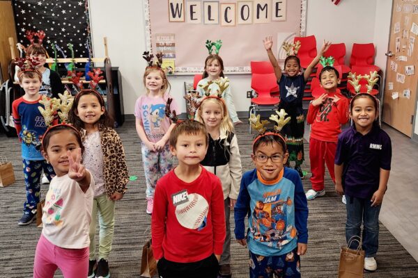 Students practice for the holiday program with reindeer antlers on their heads.