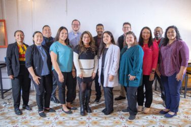A group of community leaders pose together for a photo in the YES House.
