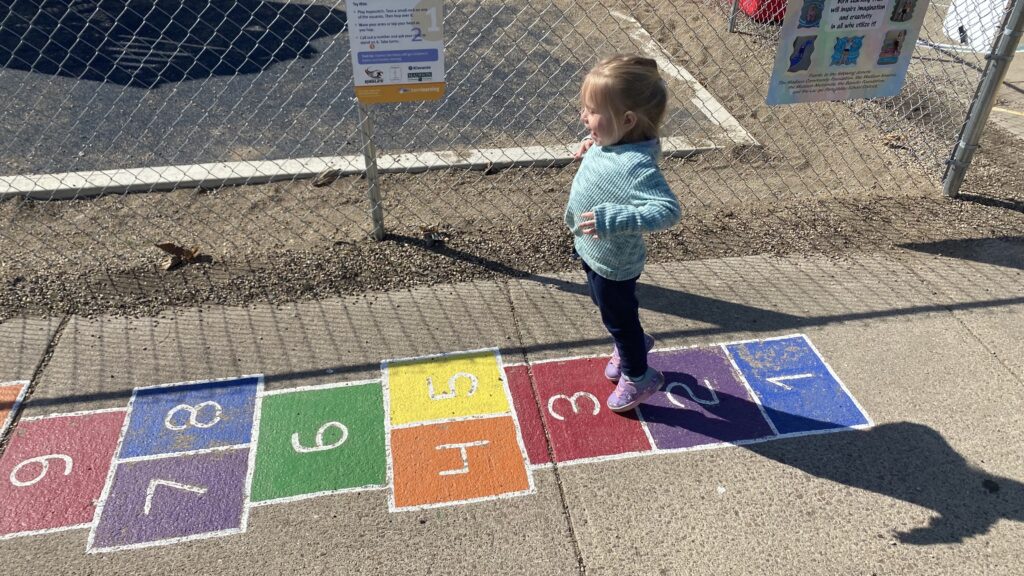 A young child gets ready to jump from one hopscotch square to the next on the Born Learning Trail in Madison.