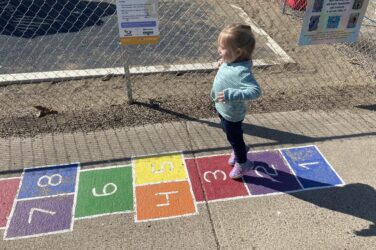 A young child gets ready to jump from one hopscotch square to the next on the Born Learning Trail in Madison.