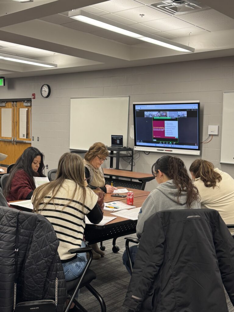 Several people sit around a table looking at papers during a leadership class.