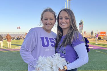 Scholarship recipients Morgan and Ashlyn are decked out in school spirit wear and hold white pom-poms.