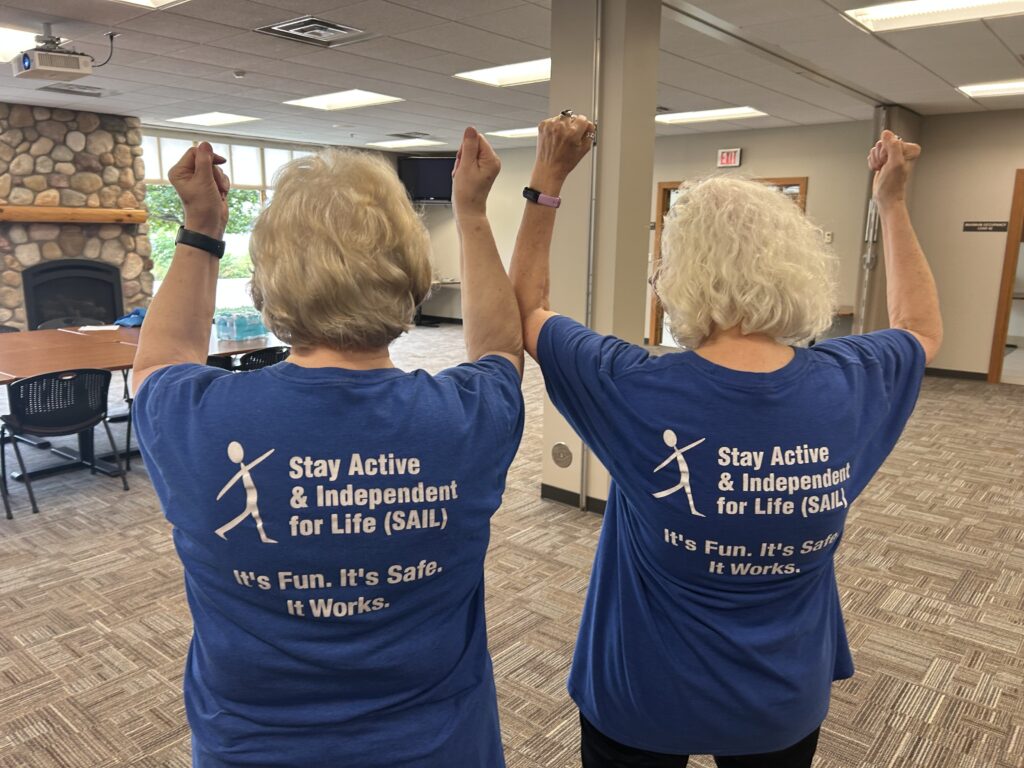 Trained volunteer leaders Elaine and Carolyn show off the back of their blue shirts.